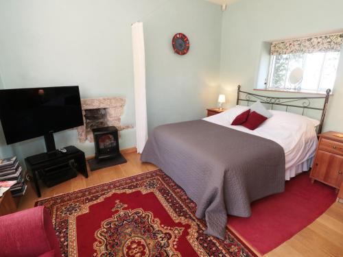 a bedroom with a bed and a television and a fireplace at Cobbled Corner in Elton