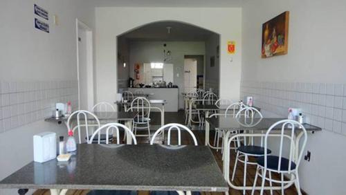 a room with tables and chairs and a kitchen at Hotel Pousada Executiva Itabuna in Itabuna