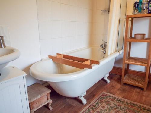 a bathroom with a white tub and a sink at Lothlorien Cottage in Garnant