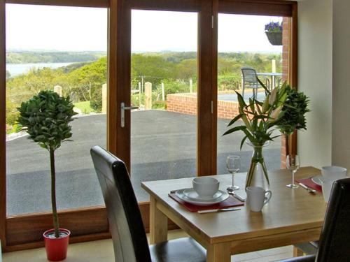 a dining room table with a view of a patio at Ysgubor Penrallt in Y Felinheli
