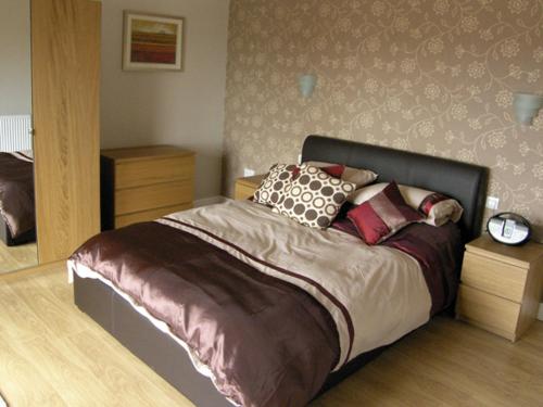 een slaapkamer met een groot bed met kussens erop bij Ysgubor Penrallt in Y Felinheli