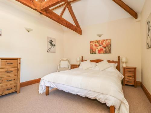 a bedroom with a large white bed and a wooden dresser at Wheelhouse Cottage in Bagby