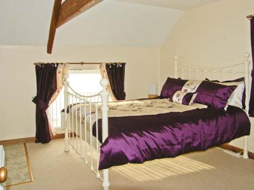 a bedroom with a white bed with purple sheets at Croft Granary in Stillington