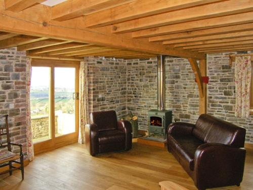 a living room with two leather chairs and a fireplace at Hiraeth in Penybont