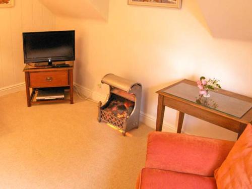 a living room with a fireplace and a tv at Brock Cottage in Beaulieu