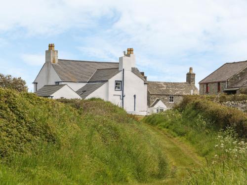 a white house on top of a grassy hill at Ty Fferm Bodlasan in Llanfachraeth