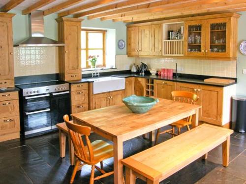 una cocina con una mesa de madera y un tazón. en Ysgubor Pwlliago, en Pennant-Melangell