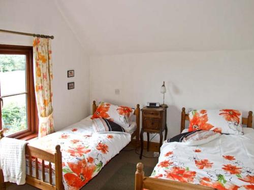リークにあるHighfield Cottageのベッドルーム1室(ベッド2台、テーブル、窓付)