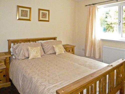 a bedroom with a large white bed with a window at Braewood in Invermoriston