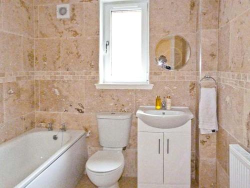 a bathroom with a toilet and a sink and a tub at Braewood in Invermoriston