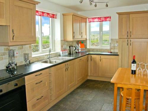 a kitchen with wooden cabinets and a table with a bottle of wine at Bryn Re in Trawsfynydd