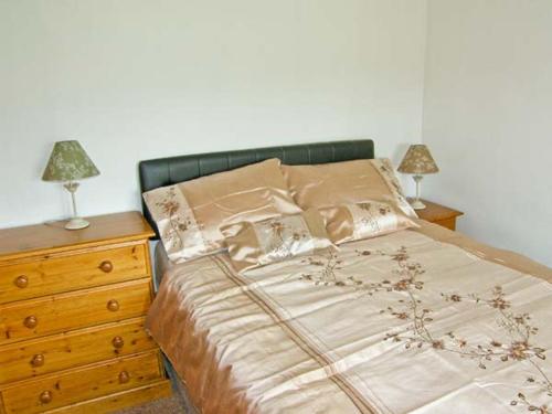 a bedroom with a bed with two lamps and a dresser at Bryn Re in Trawsfynydd