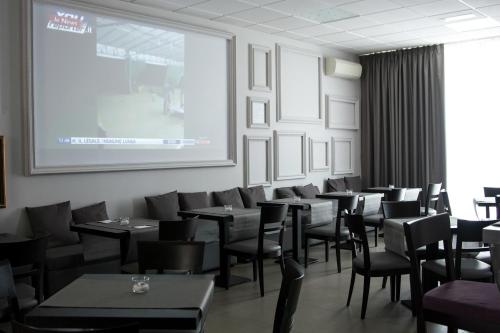 a room filled with tables and chairs and a projector screen at Hotel Castelmartini in Larciano