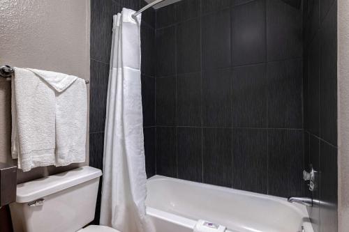 La salle de bains est pourvue d'une douche et de toilettes blanches. dans l'établissement Motel 6-Buttonwillow, CA Central, à Buttonwillow