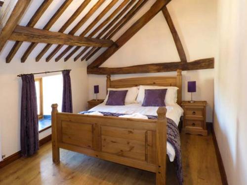 a bedroom with a wooden bed in a attic at Bwthyn Y Wennol in Llanddulas