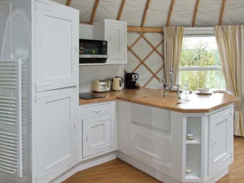 a kitchen with white cabinets and a wooden counter top at Lakeview Yurt in Beckford