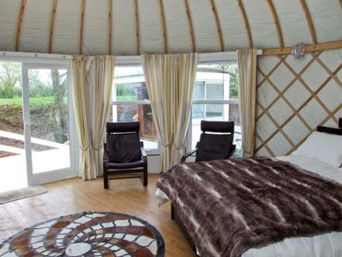 a bedroom with a large bed and two chairs at Lakeview Yurt in Beckford