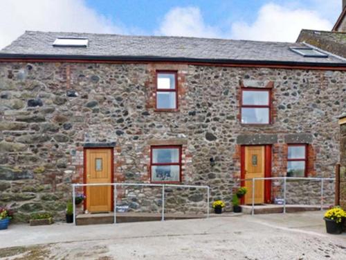 a stone house with orange doors and windows at Gable View in Drigg