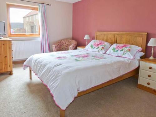 a bedroom with a large bed and a window at Cooper Cottage in Potto