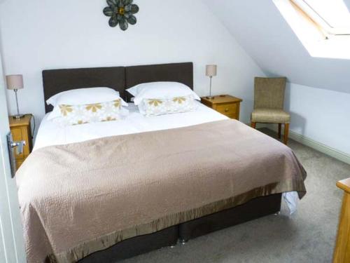 um quarto com uma cama grande e uma cadeira em Muirmailing Cottage em Plean