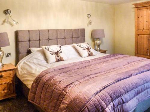 a bedroom with a large bed with a purple blanket at Orcaber Cottage in Austwick