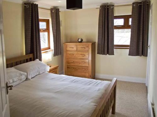 a bedroom with a bed and a dresser and a window at Hartam House in Falstone