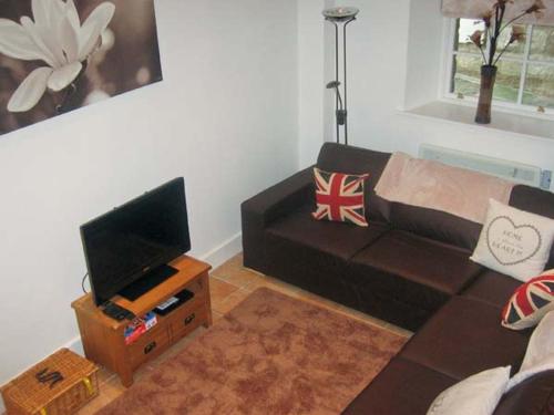 uma sala de estar com um sofá e uma televisão em No 5 The Stables em Pateley Bridge