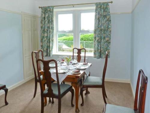 a dining room with a table and chairs and a window at Priory View in Bardsea