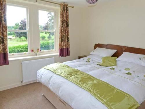 a bedroom with a bed and two windows at Priory View in Bardsea