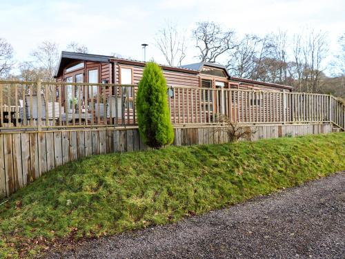 a wooden fence with a house in the background at The Four Oaks Chalet in Fassfern
