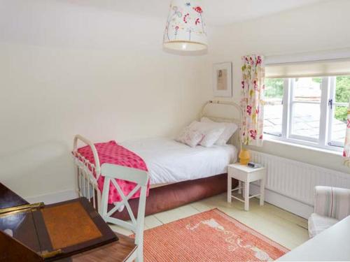 een kleine slaapkamer met een bed en een raam bij Woodhill Cottage in Holmbury Saint Mary