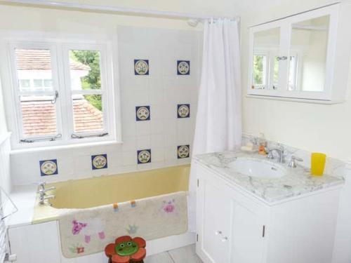 een witte badkamer met een wastafel en een bad bij Woodhill Cottage in Holmbury Saint Mary