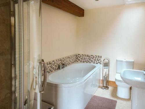a bathroom with a tub and a toilet and a sink at Riddings Barn in Low Borrowbridge