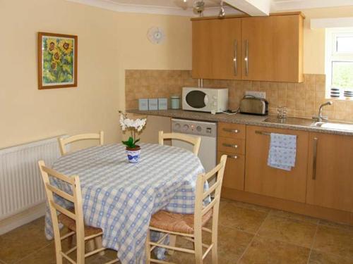a kitchen with a table and chairs and a kitchen with a table and a table at Glan Y Don Bach in Abersoch