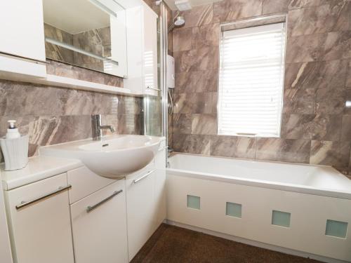 a bathroom with a sink and a bath tub and a mirror at Hunters Moon Annexe in Fulford
