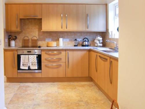 a kitchen with wooden cabinets and a stove top oven at Glan Y Don in Abersoch