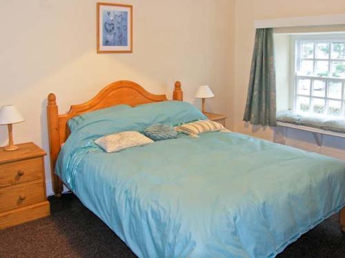 a bedroom with a bed with blue sheets and a window at Glan Y Don in Abersoch