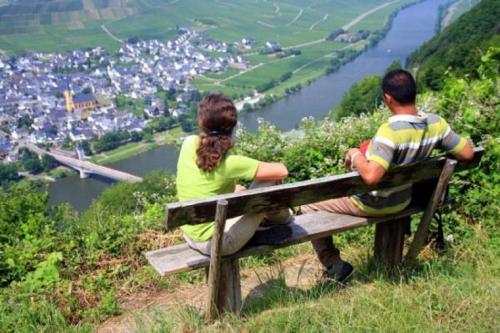 a man and woman sitting on a bench overlooking a city at Hotel Weinhaus Weis in Leiwen