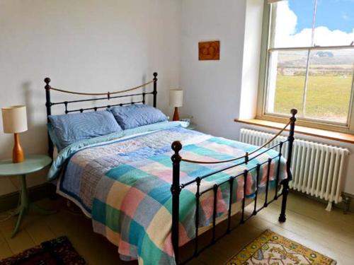 a bedroom with a bed with a colorful blanket and a window at Raceside Farm in Silecroft