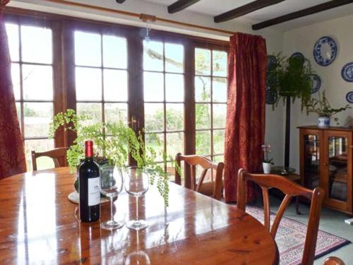 a dining room table with a bottle of wine on it at Coles Cottage in Holsworthy