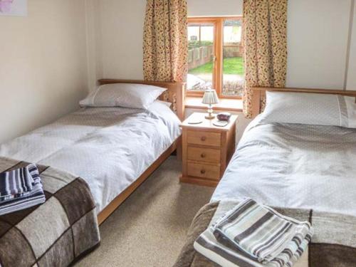 a bedroom with two beds and a window at 1 Woods Garth in Wetwang
