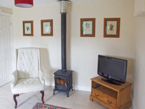 a living room with a tv and a chair and a stove at Hollins Wood Bothy in Wortley