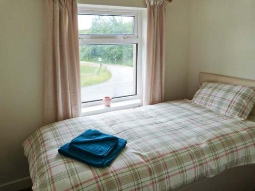 a bed with a blue towel on it next to a window at 4 Helwith Bridge Cottages in Horton in Ribblesdale