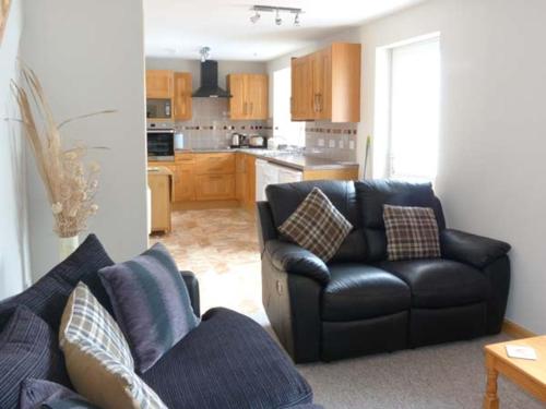 uma sala de estar com um sofá e uma cozinha em The Croft House em Muir of Ord