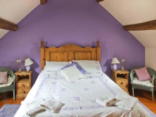 Horse Shoe Cottage في Bradley in the Moors: غرفة نوم بسرير كبير وبجدار ارجواني