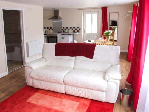 un sofá blanco en una sala de estar con cortinas rojas en Rowan Studio, en Great Witcombe