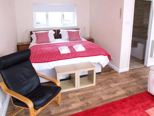 a bedroom with a bed with a table and a chair at Rowan Studio in Great Witcombe