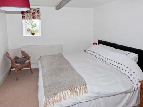a bedroom with a white bed and a chair at Knowle Lodge in Mytholmroyd