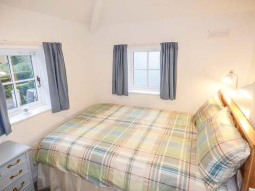 a small bedroom with a bed and two windows at Old Church Coach House in Church Leigh