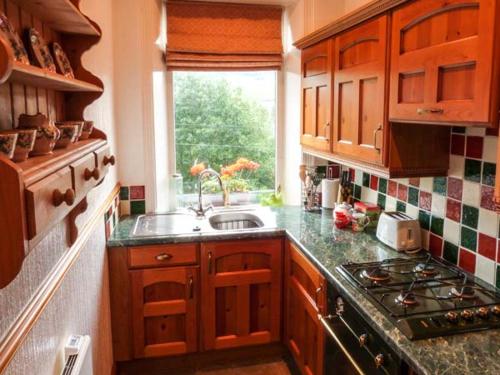 a kitchen with a sink and a stove and a window at Cottage in the Sky in Luddenden Foot